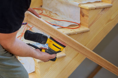 Midsection of man working on wood at home