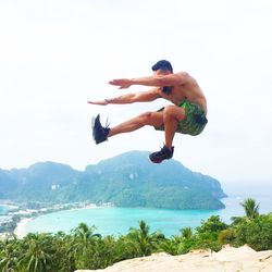 Man jumping over sea against sky