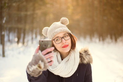 Close-up of woman wearing hat holding ice cream standing in snow