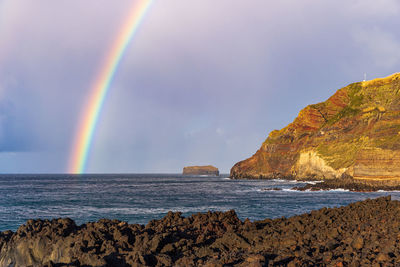 Rainbow arching out of the atlantic ocean at ponta da ferraria, sao miguel island, azores, portugal