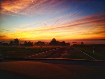 Road against sky during sunset seen through car windshield