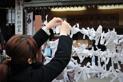 Rear view of woman tying paper at temple