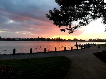 Silhouette trees by lake against sky during sunset