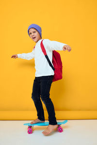 Portrait of young woman exercising against yellow background