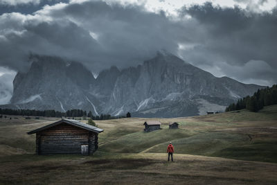 Rear view of man standing on field against mountains and sky