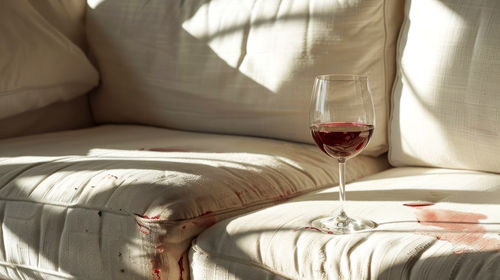 Midsection of woman holding wineglass on bed at home