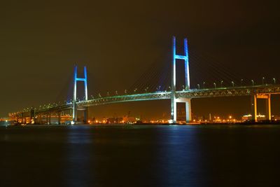 Illuminated suspension bridge over river at night