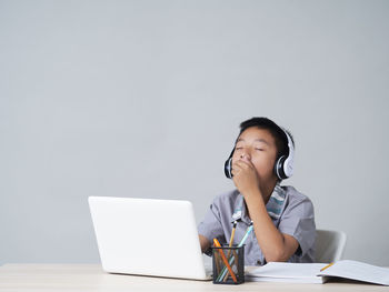 Young woman using mobile phone while sitting on table