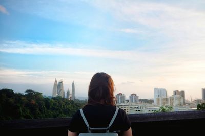 Rear view of backpack woman looking at cityscape