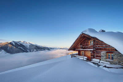 House on snowcapped mountain against clear blue sky