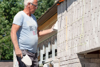 Masonry worker the bricklayer makes the facade of the house from gray bricks