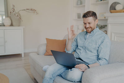 Young woman using mobile phone while sitting on sofa at home