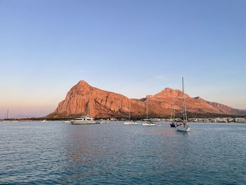 Sailboats in sea against clear blue sky