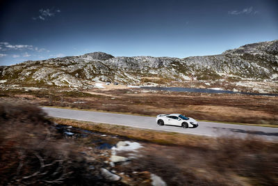 Car on road by mountain against sky