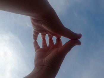 Cropped hands of people against sky