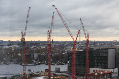 Cranes at construction site against sky in city