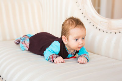 Portrait of cute boy lying on bed at home