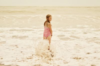 Rear view of girl standing at beach