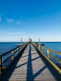 Pier over sea against blue sky