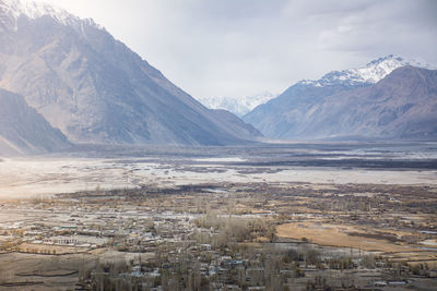 Scenic view of landscape by mountains against sky