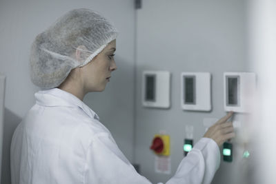 Woman in protective workwear operating machine