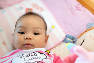 Portrait of cute baby girl lying on bed at home