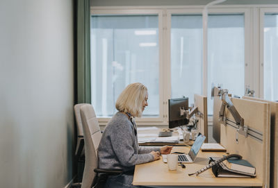 Smiling woman using laptop in office