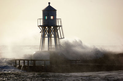 Lighthouse by sea against sky