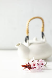 Pink flowers with teapot in background on table