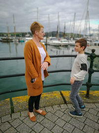 Side view of boy standing by water with his grandma 