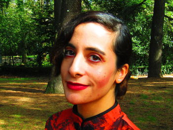 Portrait of smiling young woman against tree trunk
