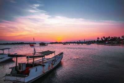 Boats moored in sea at sunset