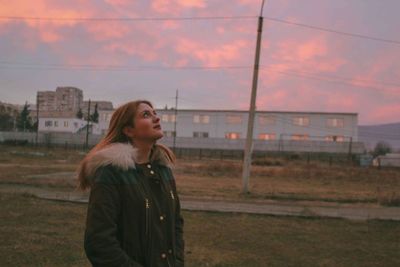 Young woman standing on field during sunset