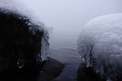 Frozen rock at lake against sky