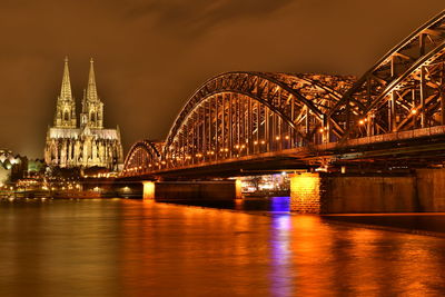 Illuminated bridge over river at night