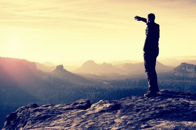 Man standing on mountain against sky during sunset