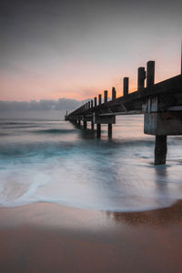 Pier over sea against sky during sunset