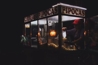 Rear view of man standing at illuminated restaurant