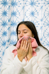 Hispanic woman in a robe drying her face with a pink towel