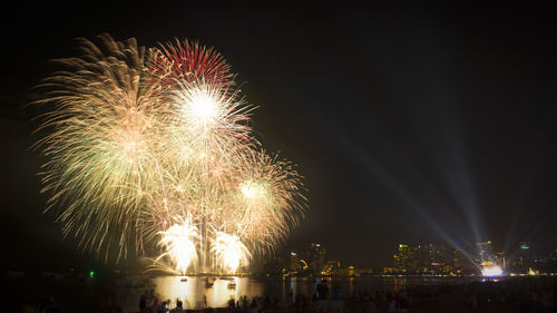 Firework display over river against sky at night