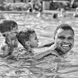 Portrait of father swimming in pool with sons