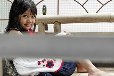 Portrait of smiling girl sitting over wooden walkway