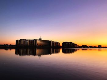 Reflection of buildings in lake against clear sky