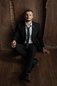 Portrait of young man sitting on wooden floor