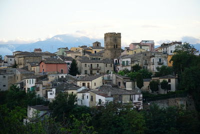 Houses and trees in city against sky