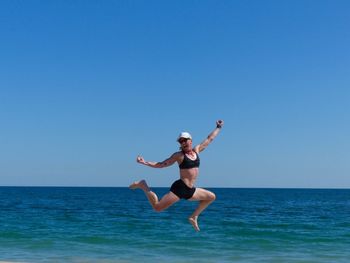 Silhouette of woman jumping in sea