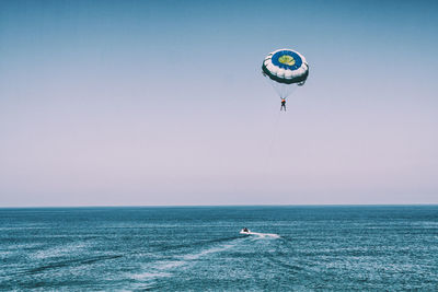 Person parasailing over sea against sky