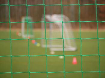 Soccer football net background over green grass and blurry stadium. close up detail of a soccer net 