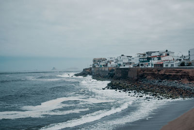 Buildings by sea against sky