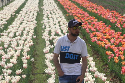 Full length of young man standing by flowering plants